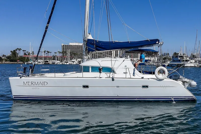 Slide: The Image of 2004 Lagoon 380 catamaran named "Mermaid" sailing in a marina under clear blue skies. - 9