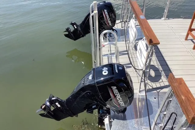 Slide: The Image of Twin Mercury outboard motors on a 2023 Big Hut 26 boat, docked on calm water. - 5