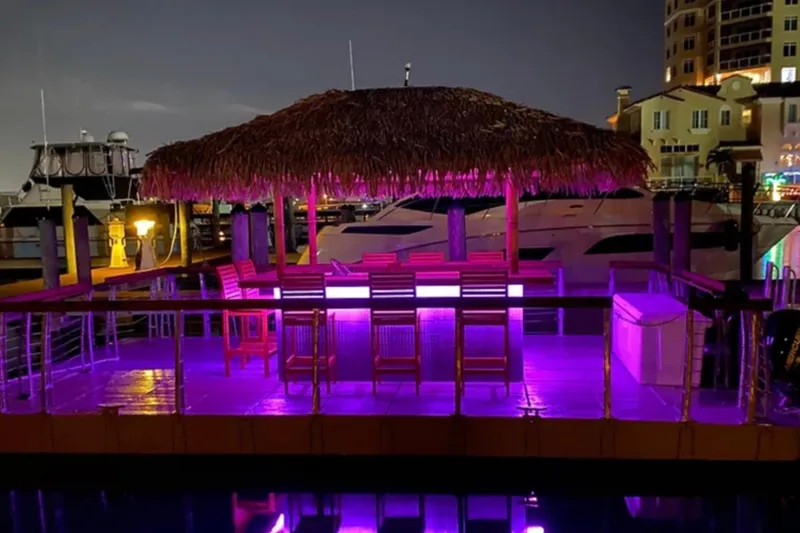 Slide: The Image of Floating tiki bar with purple lighting, Big Hut 26 model, 2023, docked at night. - 7