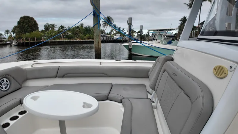 Slide: The Image of 2017 Tidewater 252 LXF boat interior with seating and table, docked by palm trees. - 30