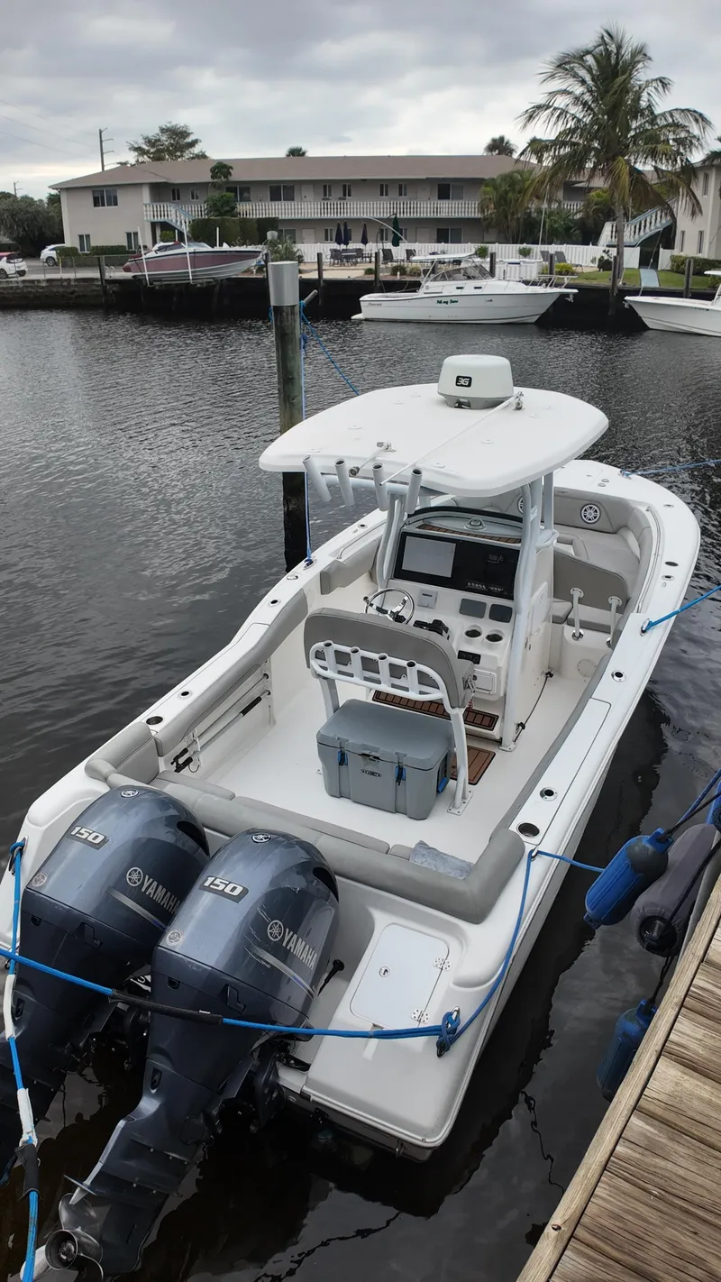 Slide: The Image of 2017 Tidewater 252 LXF boat docked by waterfront homes, featuring dual outboard engines. - 35