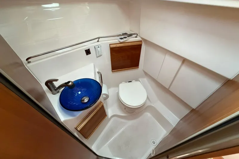 Slide: The Image of 2019 Cutwater C-28 boat bathroom with blue glass sink and compact toilet. - 12