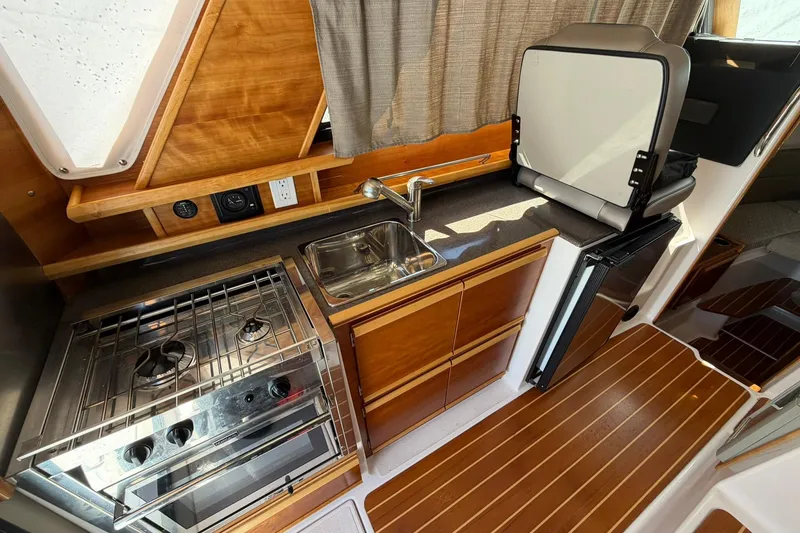 Slide: The Image of 2019 Cutwater C-28 boat interior kitchen with stove, sink, and compact fridge. - 6