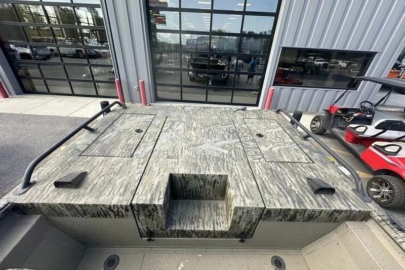 Slide: The Image of 2025 SeaArk Predator 300 AK boat with camo deck, parked near a garage. - 12