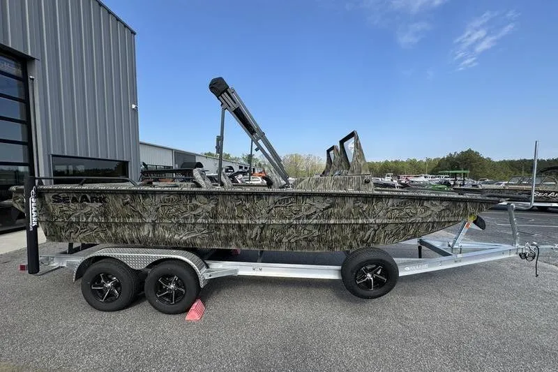 Slide: The Image of 2025 SeaArk Predator 300 AK boat on trailer, camo design, parked outdoors. - 14