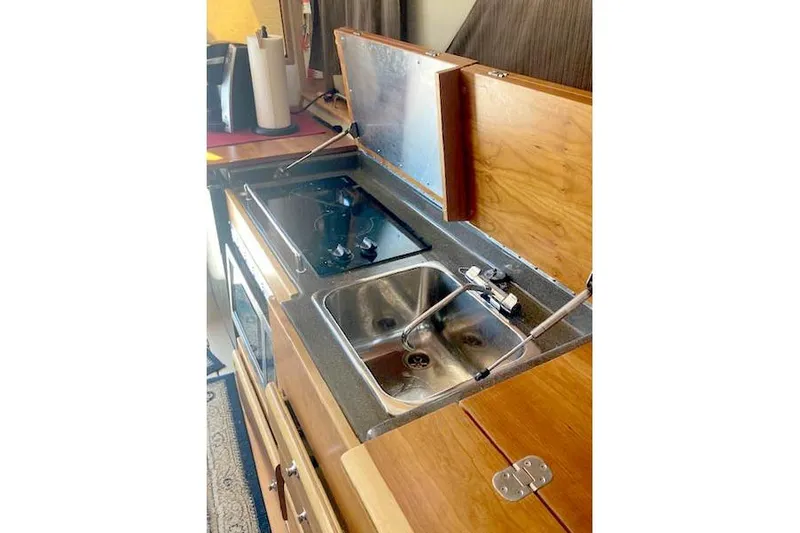 Slide: The Image of 2018 Cutwater C-30 Sedan kitchen with stove and sink, featuring wooden cabinetry. - 19