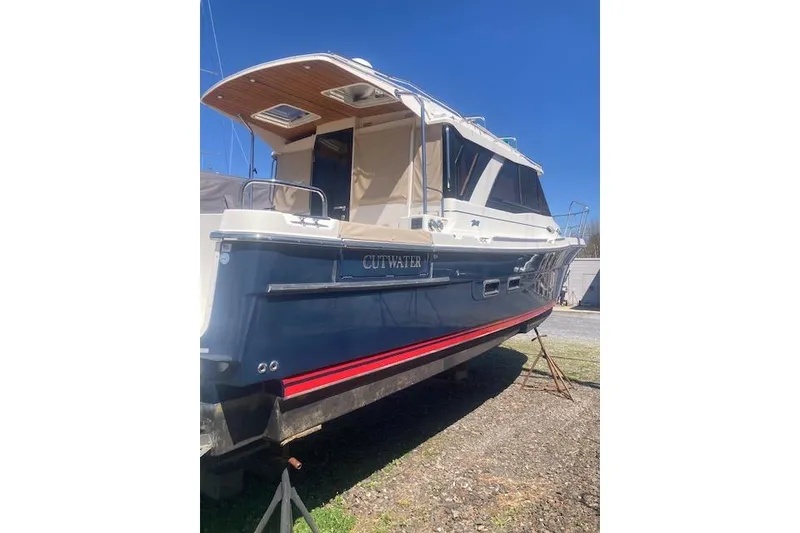 Slide: The Image of 2018 Cutwater C-30 Sedan boat on land, blue hull, red stripe, sunny day. - 3