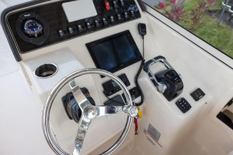 Slide: The Image of 2018 Grady-White Freedom 285 boat dashboard with steering wheel and controls. - 11