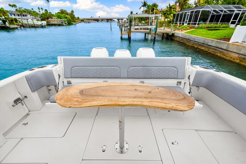 Slide: The Image of 2019 Intrepid 410 Evolution boat deck with wooden table, overlooking serene waterfront. - 21
