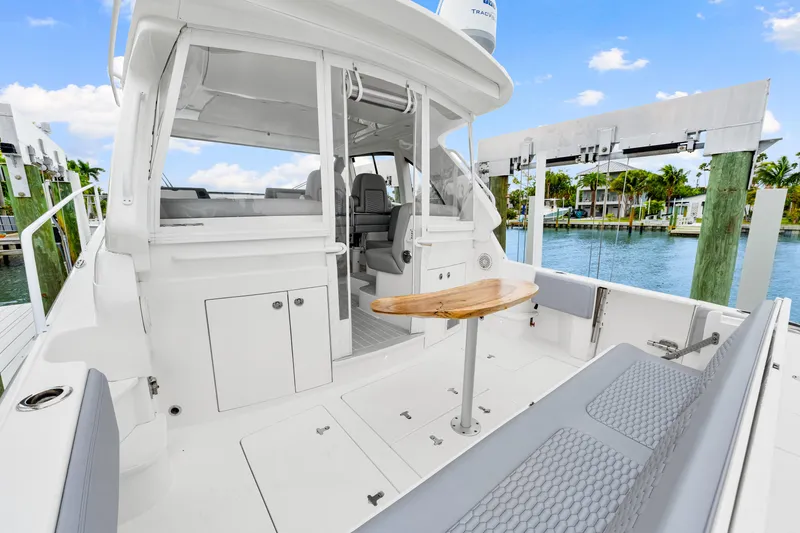 Slide: The Image of 2019 Intrepid 410 Evolution yacht interior with seating and table, docked by the water. - 23