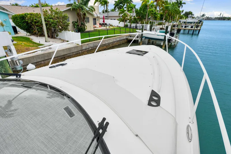 Slide: The Image of 2019 Intrepid 410 Evolution yacht docked by waterfront homes and lush greenery. - 32