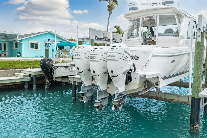 Slide: The Image of 2019 Intrepid 410 Evolution boat with triple Mercury engines docked by turquoise water. - 4