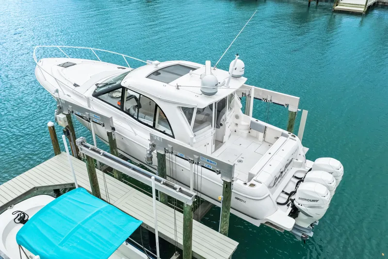 Slide: The Image of 2019 Intrepid 410 Evolution boat on lift, docked in clear blue water. - 8