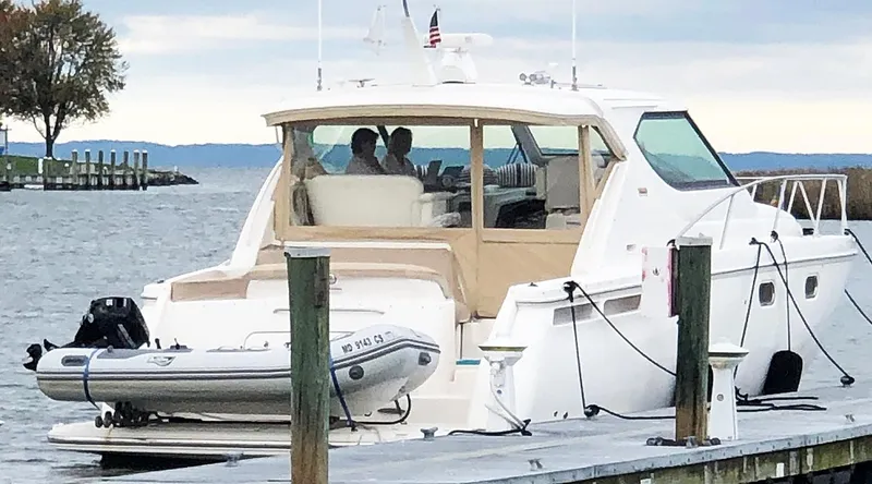 Slide: The Image of 2009 Tiara Yachts 4300 Sovran docked with inflatable boat, scenic waterfront view. - 18