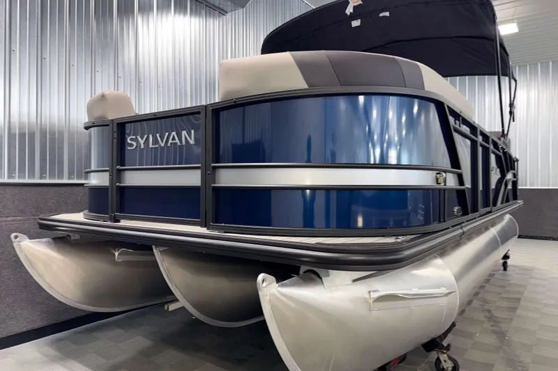 Slide: The Image of 2026 Sylvan L1 LZ pontoon boat in showroom, featuring sleek blue and silver design. - 22