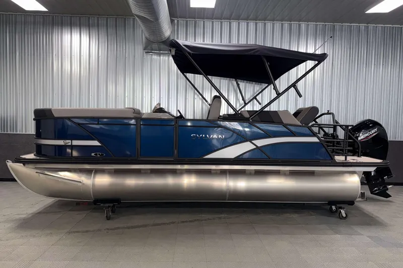 Slide: The Image of 2026 Sylvan L1 LZ pontoon boat with blue exterior and canopy in a showroom. - 24