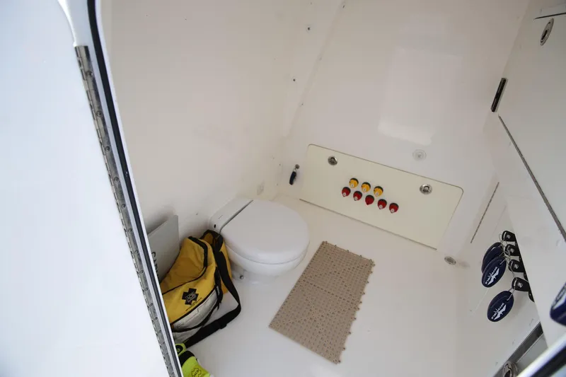 Slide: The Image of Interior of 2020 Invincible 35 Catamaran showing a compact marine toilet and storage area. - 27
