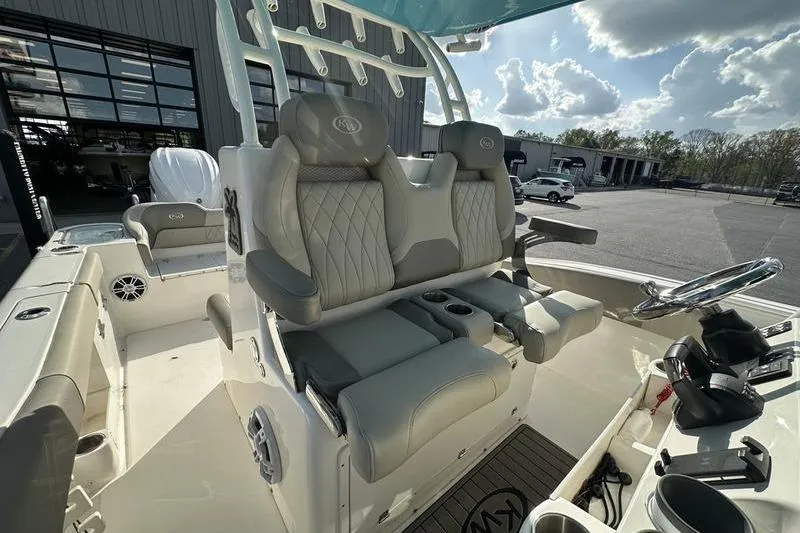 Slide: The Image of 2024 Key West 291 FS boat interior with seating, parked outdoors under a cloudy sky. - 16