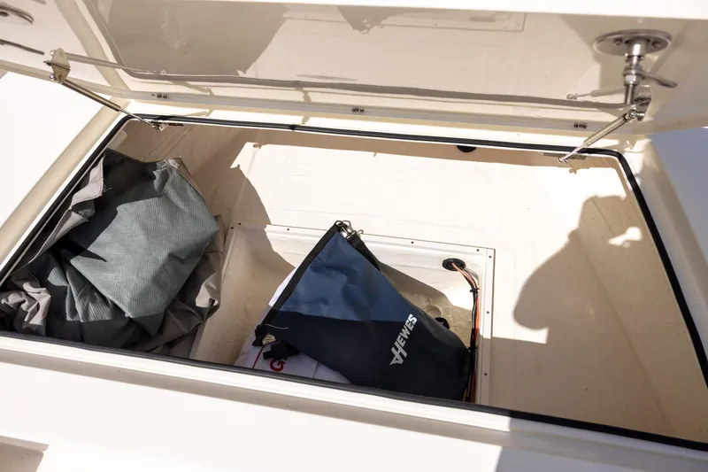 Slide: The Image of Open storage compartment in 2025 Hewes Redfisher 21 boat with gear bags inside. - 10