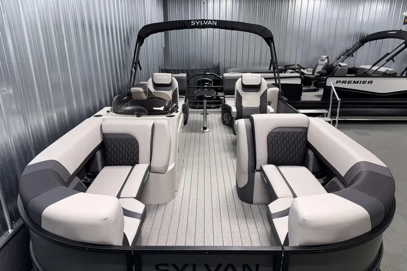 Slide: The Image of 2026 Sylvan L1 LZ pontoon boat with luxurious seating in a showroom. - 2
