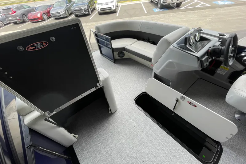 Slide: The Image of 2026 Harris Cruiser 210 SLDH interior with seating and helm, parked in a lot. - 3