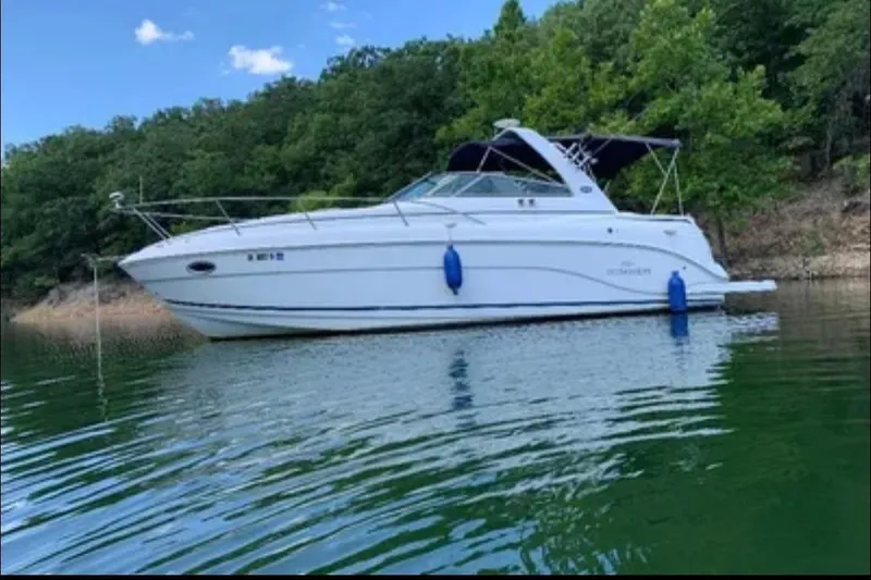 The Image of 2006 Rinker 300 Express Cruiser on a serene lake with lush green trees. - 0