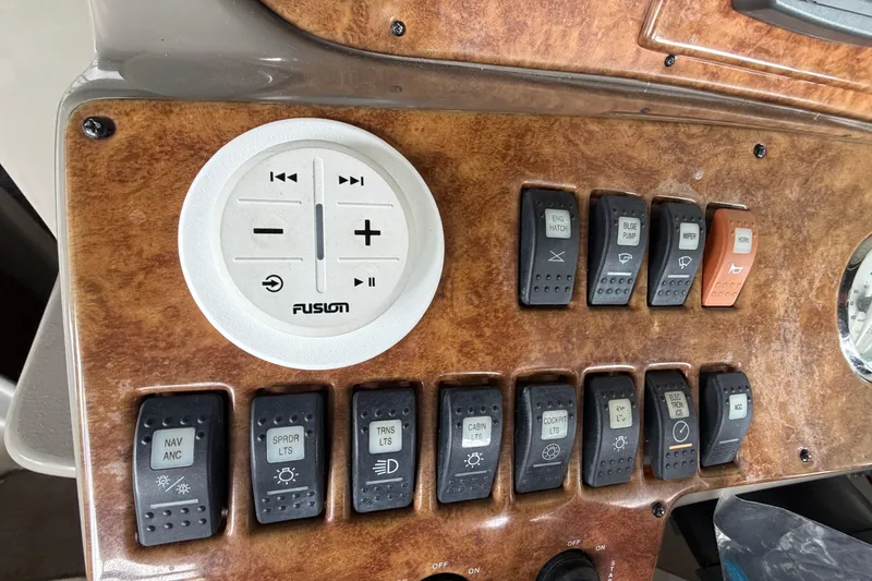 Slide: The Image of Control panel of a 2006 Rinker 300 Express Cruiser with various switches and Fusion audio controls. - 15