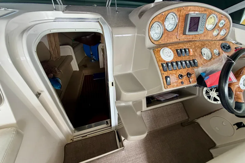 Slide: The Image of 2006 Rinker 300 Express Cruiser helm with woodgrain dashboard and cabin entrance. - 16
