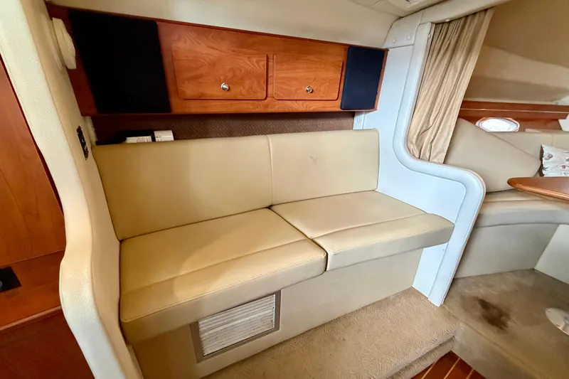 Slide: The Image of 2006 Rinker 300 Express Cruiser interior with beige seating and wooden cabinetry. - 24