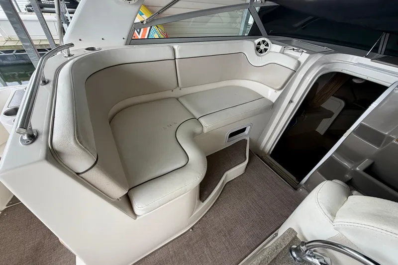 Slide: The Image of 2006 Rinker 300 Express Cruiser interior seating area with beige upholstery and cabin entrance. - 8