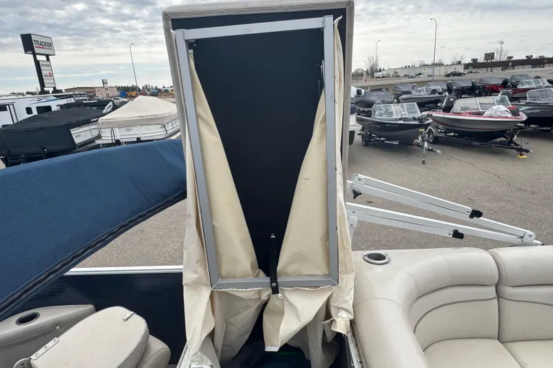 Slide: The Image of 2018 Bennington 22 SFX boat interior with seating and privacy enclosure, parked in a dealership lot. - 17