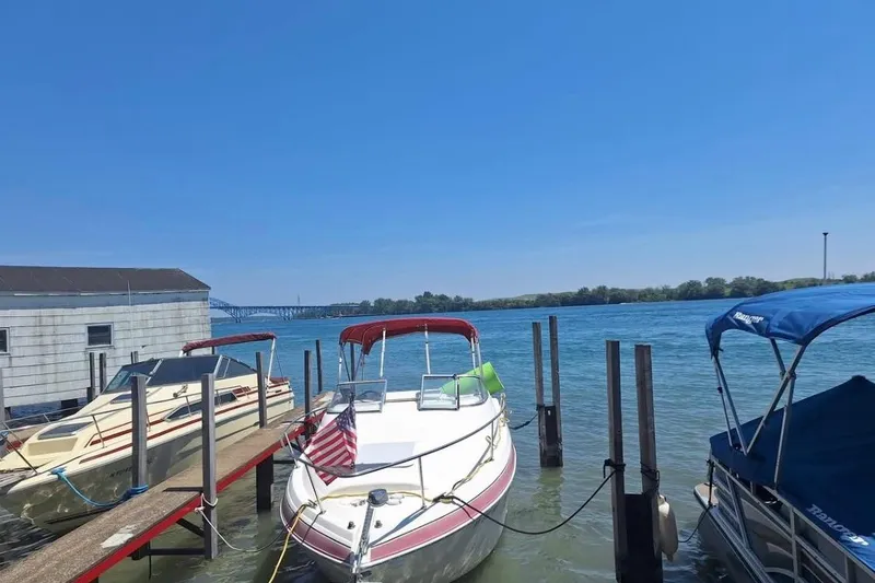 Slide: The Image of 2009 Glastron GT 249 boat docked by a serene waterfront under clear blue skies. - 4
