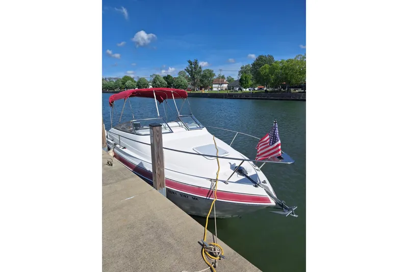 Slide: The Image of 2009 Glastron GT 249 boat docked by a serene lake with American flag. - 5