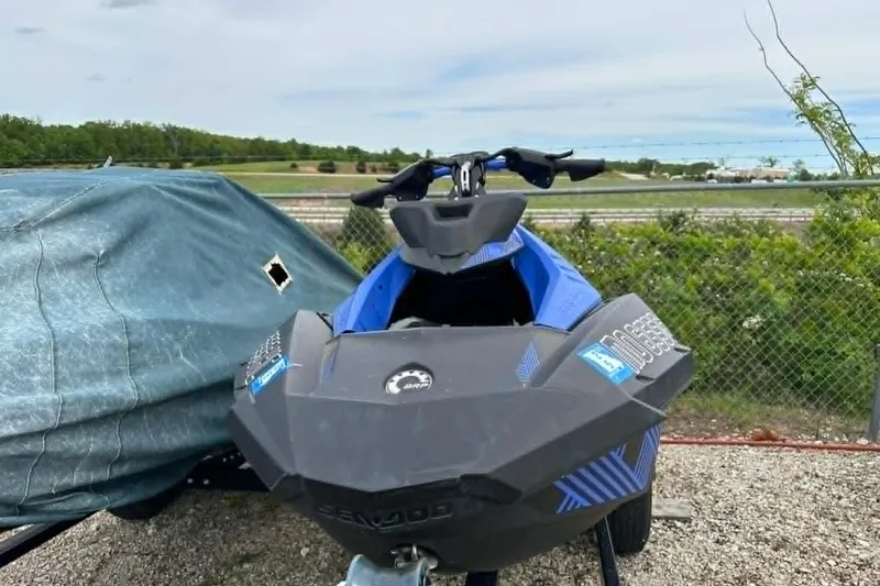 Slide: The Image of 2022 Sea-Doo Spark Trixx 2up jet ski parked outdoors near a fence. - 7