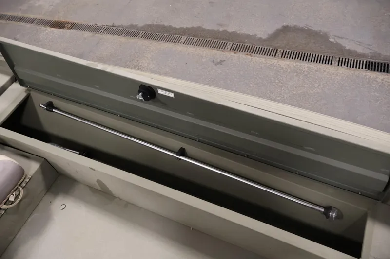 Slide: The Image of 2021 Polar Kraft Sportsman 1760 SE boat storage compartment with open lid and metal rod. - 22