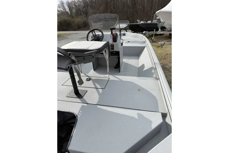 Slide: The Image of 2025 SeaArk Shadow 18T boat interior with steering console and seating, parked outdoors. - 5
