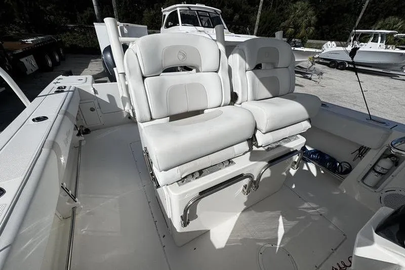 Slide: The Image of 2013 Edgewater 318CC boat interior with white cushioned seating and control area. - 16