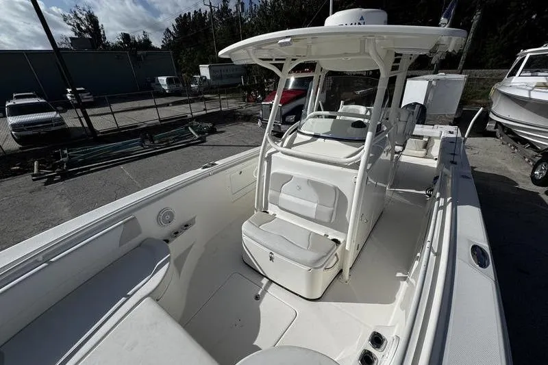 Slide: The Image of 2013 Edgewater 318CC boat interior with seating and console, parked outdoors. - 32