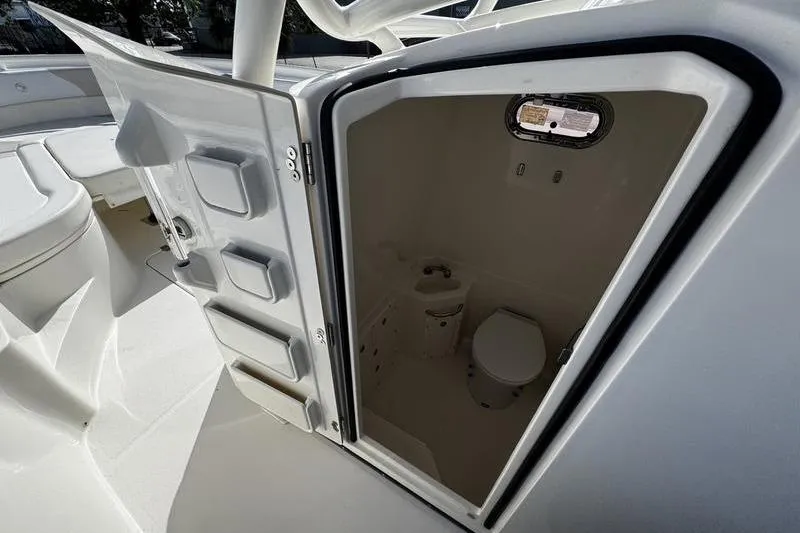 Slide: The Image of 2013 Edgewater 318CC boat interior with open door revealing compact marine toilet. - 33