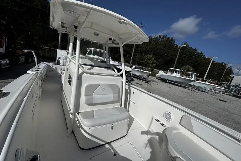 Slide: The Image of 2013 Edgewater 318CC boat interior with seating and console, parked outdoors under blue sky. - 34