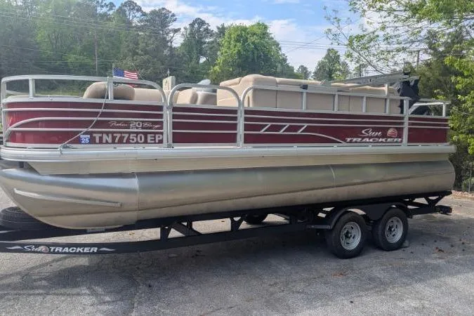 Slide: The Image of 2022 Sun Tracker Fishin' Barge 20 DLX pontoon boat on trailer, parked outdoors. - 12