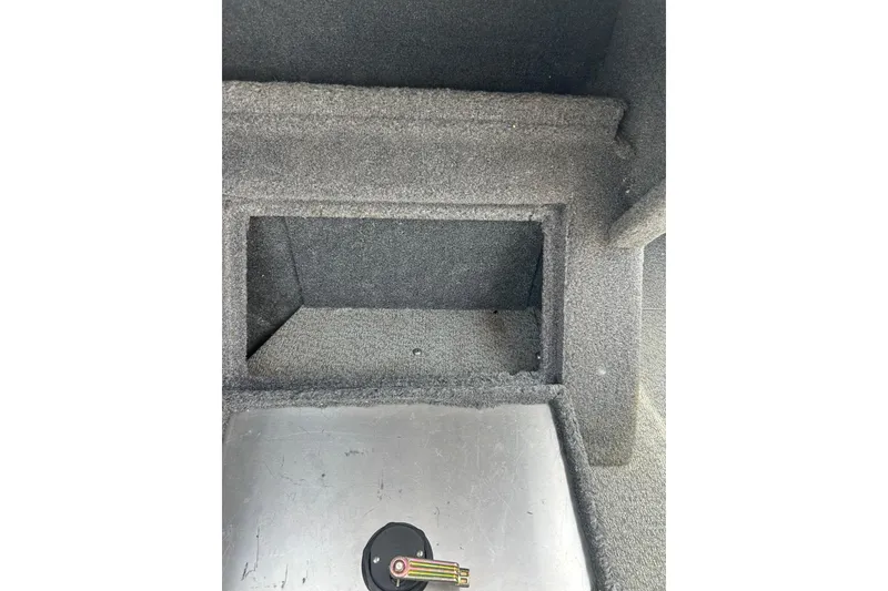 Slide: The Image of 2017 Tracker Targa V-18 Combo interior storage compartment with key on metal surface. - 20