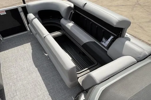 Slide: The Image of 2026 Sun Tracker Party Barge 20 DLX interior with open storage compartment and gray seating. - 7