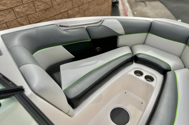 Slide: The Image of 2016 Moomba Craz boat interior with gray and white seating, green accents, and cup holders. - 12