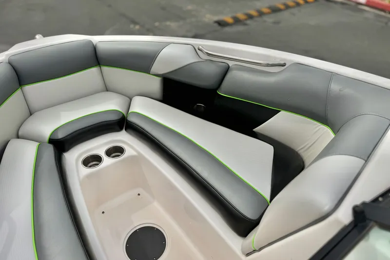 Slide: The Image of 2016 Moomba Craz boat interior with gray and white seating, green accents, and cup holders. - 13