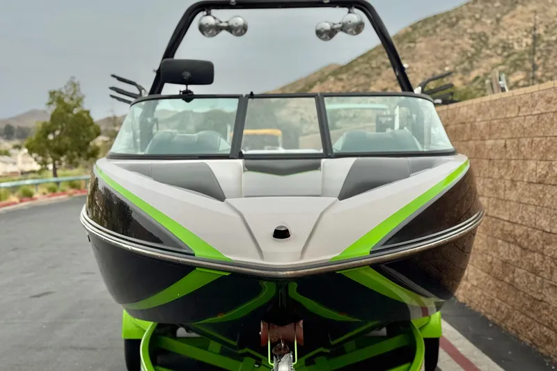 Slide: The Image of 2016 Moomba Craz boat with green accents, parked near a stone wall. - 2