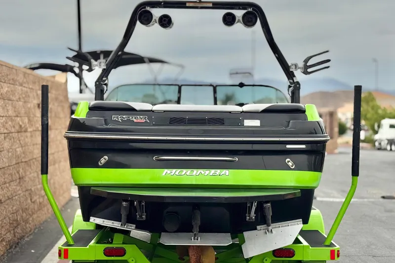 Slide: The Image of 2016 Moomba Craz boat with vibrant green accents, parked outdoors. - 4