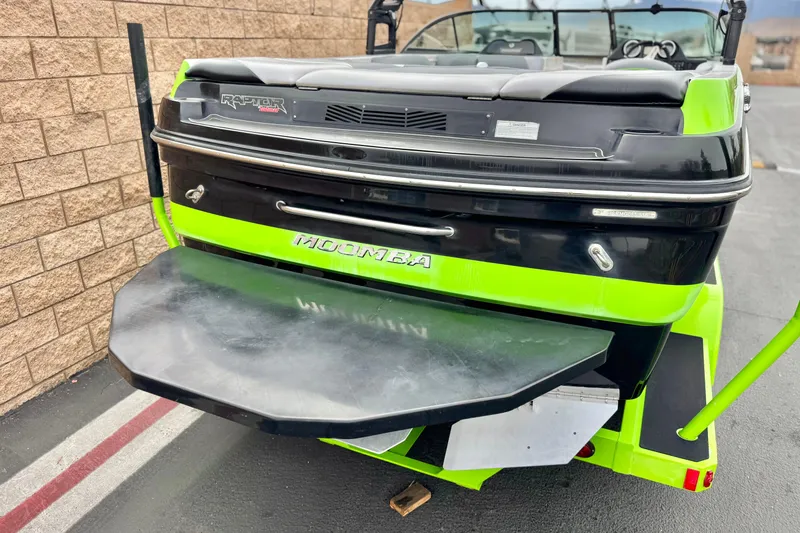 Slide: The Image of 2016 Moomba Craz boat with vibrant green and black design, parked near a brick wall. - 6