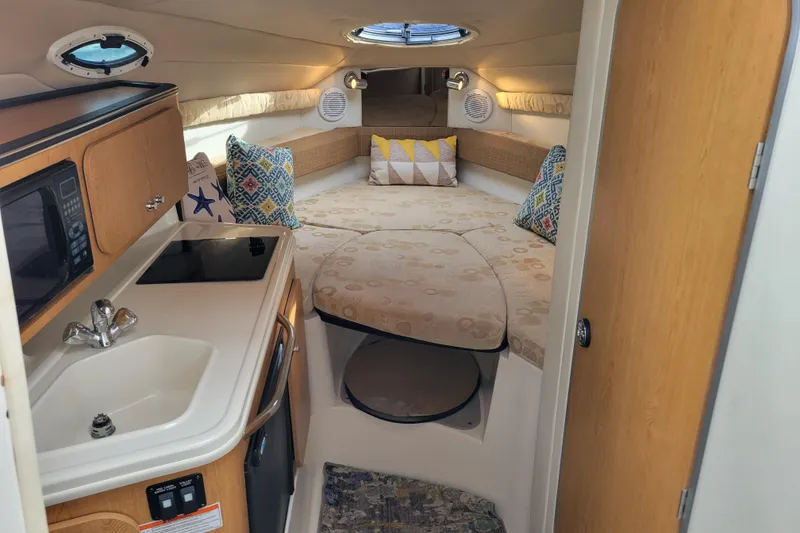 Slide: The Image of 2007 Stingray 250 CS cabin interior with kitchenette, bed, and decorative pillows. - 22