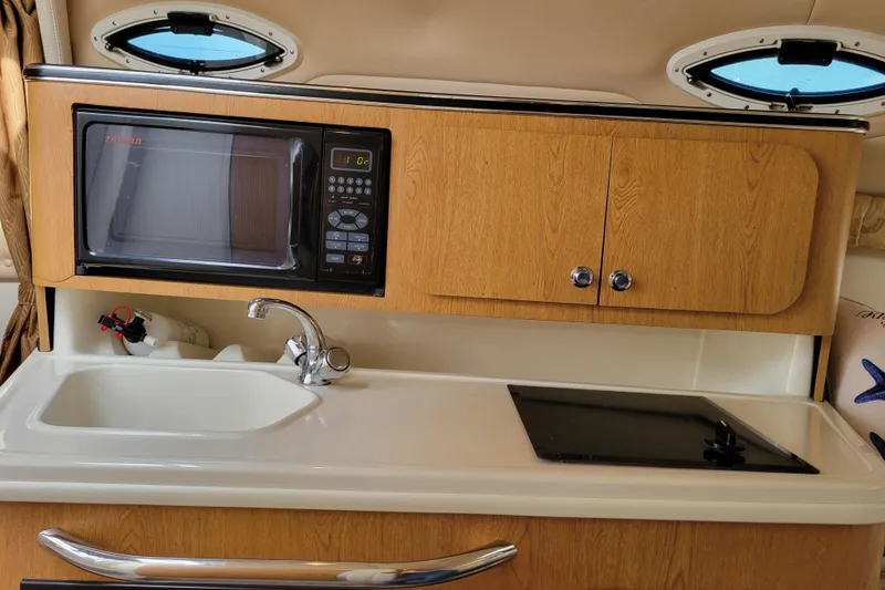 Slide: The Image of 2007 Stingray 250 CS boat kitchenette with microwave, sink, and stove. - 23
